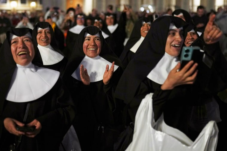 Nuns applaud as black smoke billows from the chimney 