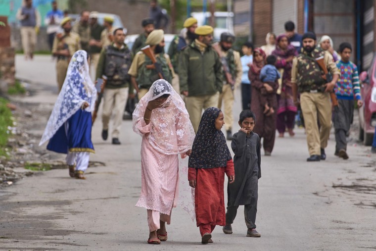 Kashmiri villagers are escorted by police as they walk after.
