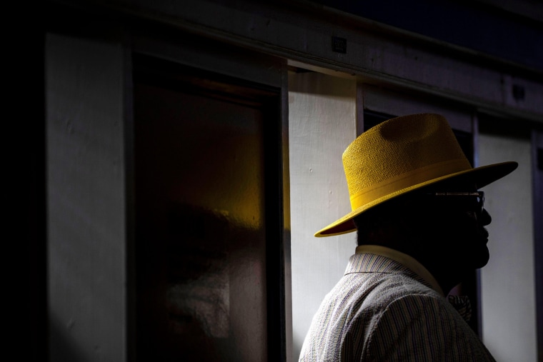 A guest in a yellow hat prepares to make a bet at Pimlico Race Course