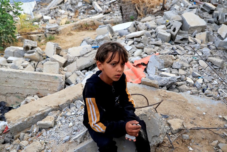 A Palestinian boy sits on rubble
