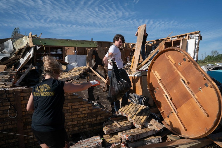 People clear debris after a tornado hit in London, Ky.