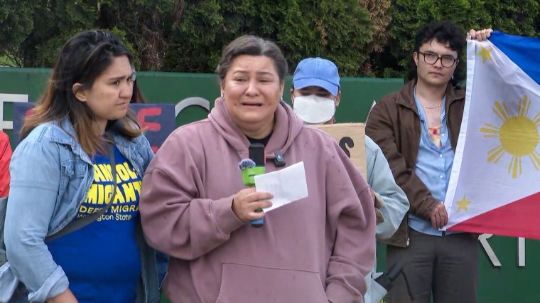 Crystal Londonio, center, speaks in front of a group of people outside, a person hold the Philippines flag behind her