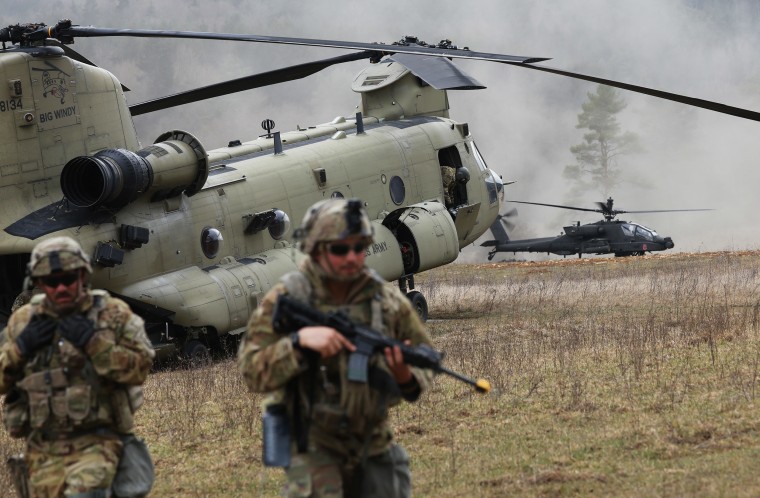 Troops, a Boeing CH-47 Chinook military transport helicopter and an Apache attack helicopte
