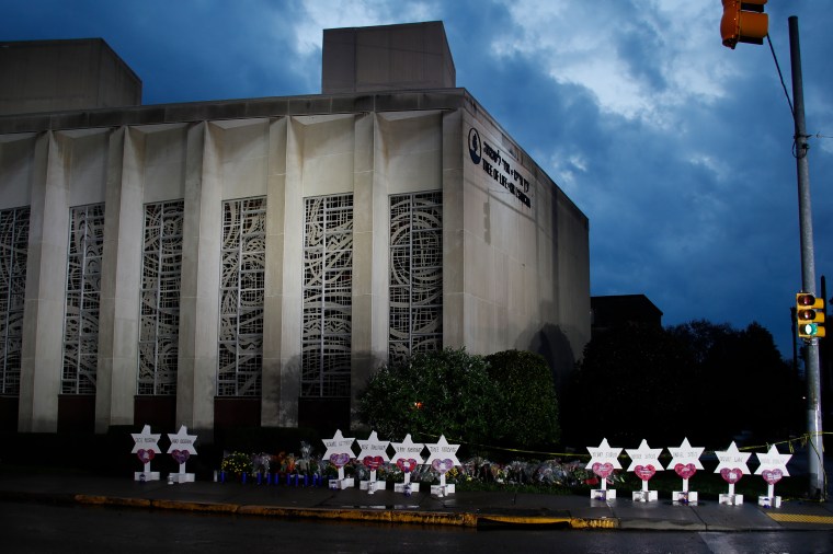 A memorial of flowers and stars line the sidewalk