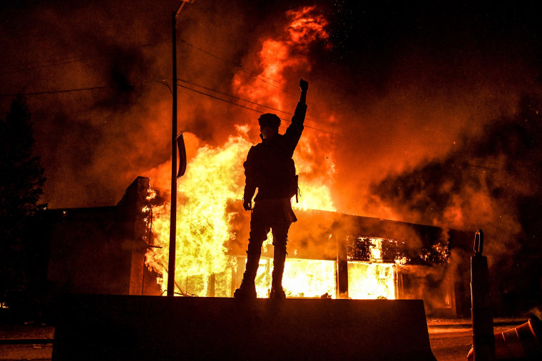 A protester reacts standing in front of a burning building set on fire during a demonstration in Minneapolis, Minnesota, on May 29, 2020, over the death of George Floyd.