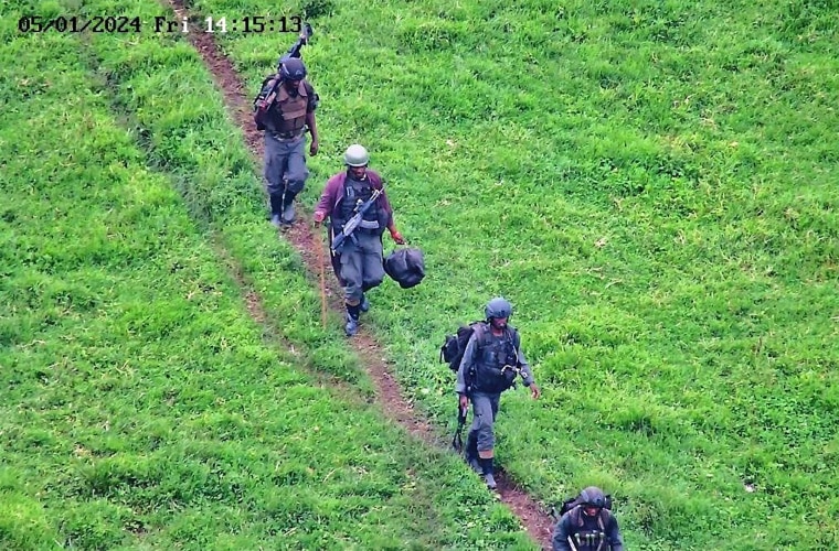 Rwandan soldiers walk across a field.
