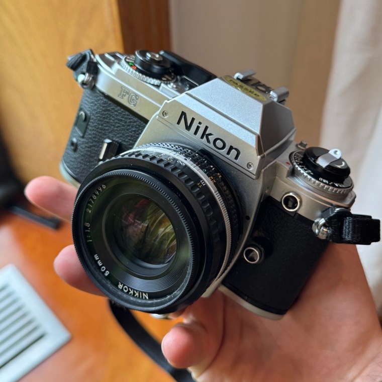 A close up of a man holding the Nikon FG camera in one hand
