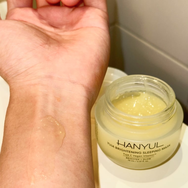 An arm with a swatch of the Hanyul yuja sleeping mask next to an open container of the product.
