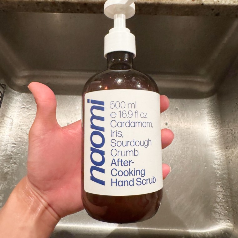 A clean hand holding the Naomi after-cooking hand scrub.