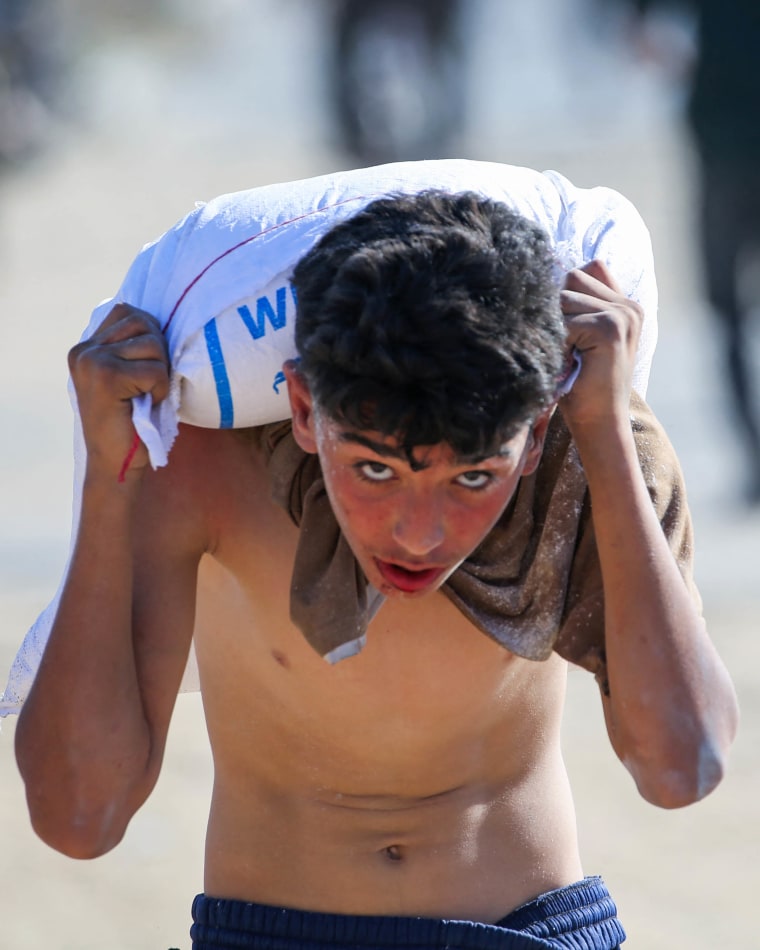 A young boy carries a bag of food aid on his shoulders