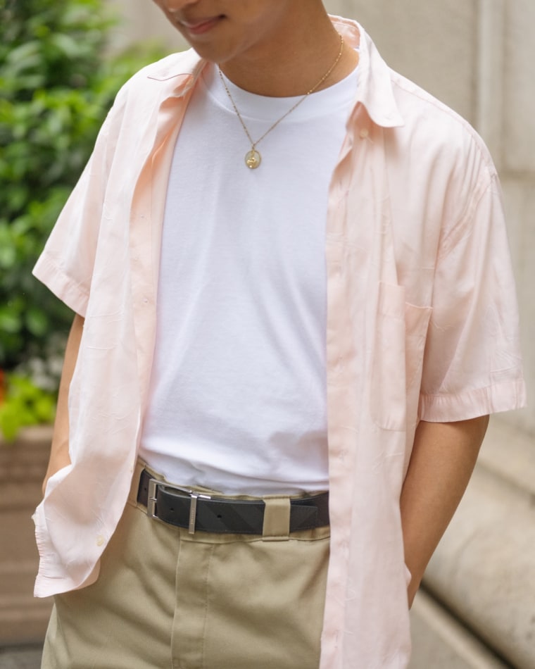 A close shot of a model wearing a white t-shirt paired with a pink colored button down shirt.