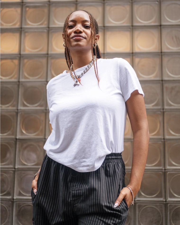 An NBC Select editor modeling a white t-shirt against a frosted glass exterior.