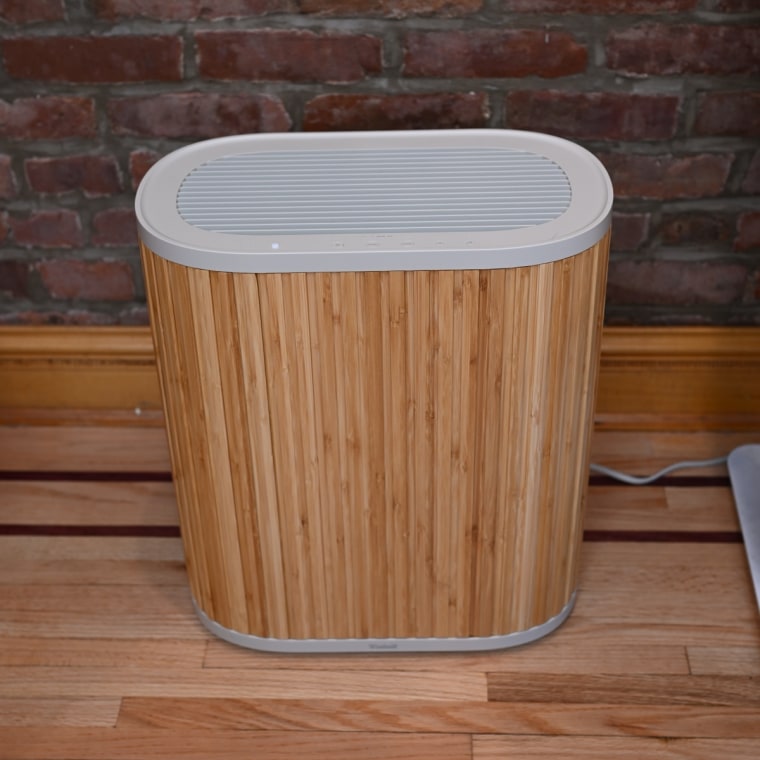 A photo of the Windmill air purifier against a wood flooring and brick wall.