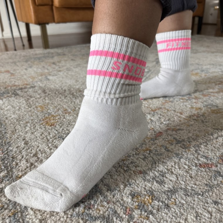 A woman wearing a pair of FitnessSnob Not Your Basic Crew socks without shoes on.