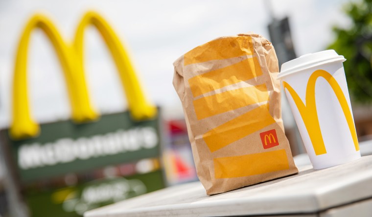 A McDonald's to-go bag and cup in front of a McDonald's.