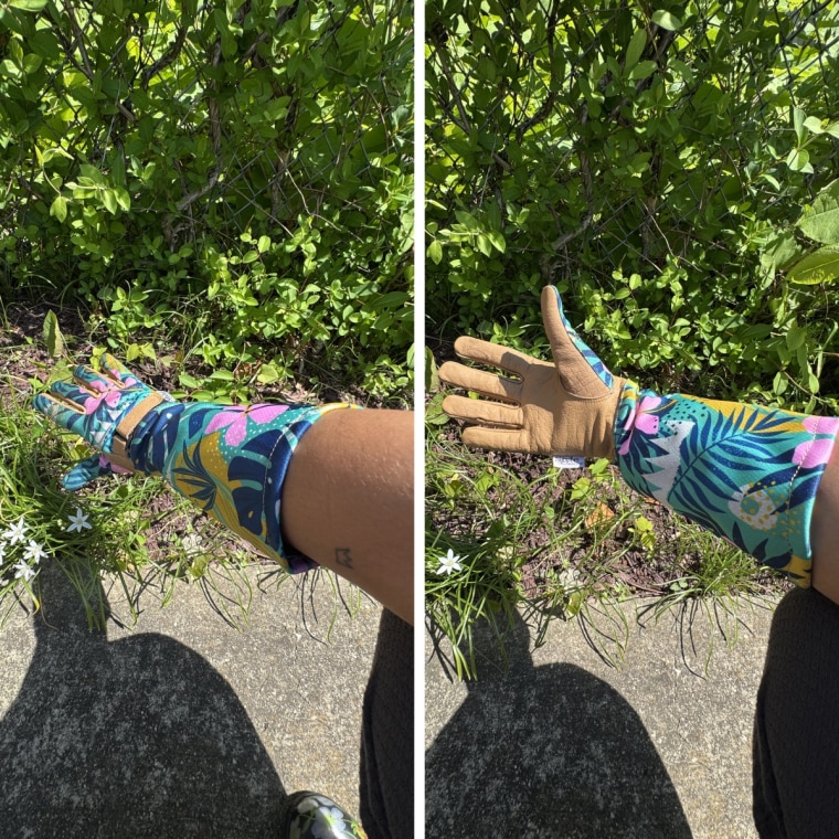 Brown wearing the tyle Selections Gardening Gloves on her right hand, held in front of a patch of greenery in a garden bed.
