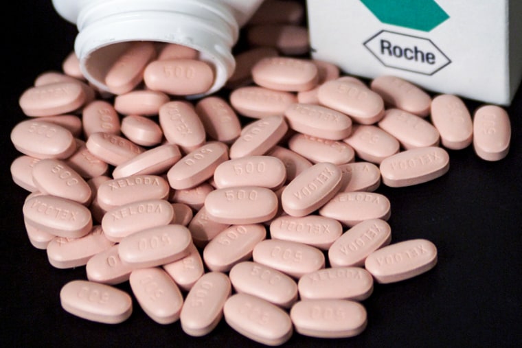Pink pills are grouped onto a black surface