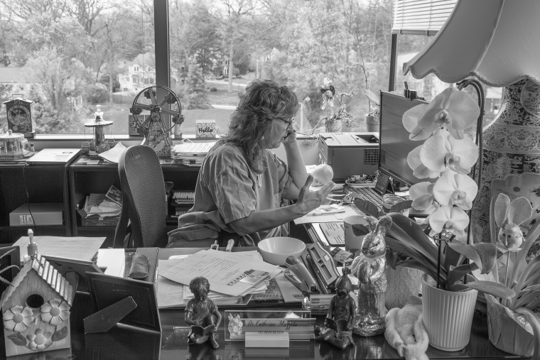 Dr. Catherine Mazzola on her phone at her desk.