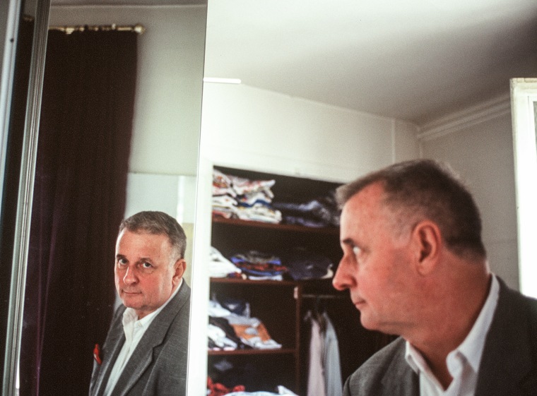 Edmund White looks at his reflection in a mirror