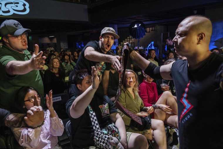 Fans reaching to touch the championship belt of wrestler The Slam before his match.