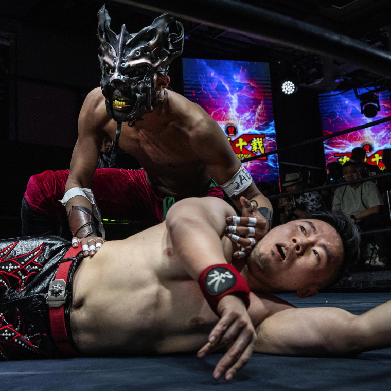 Wrestler Zombie Dragon, top, reacts as he tries to pin Coldplay during their match at the Middle Kingdom Wrestling Battle of the Decade in Beijing on May 24, 2025.