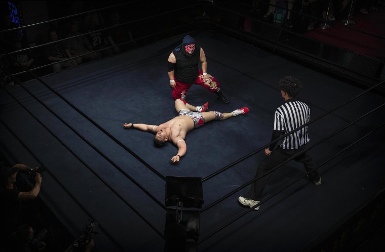 Wrestler Wade Massen crouching over Lin Dongxuan during their bout in Beijing.