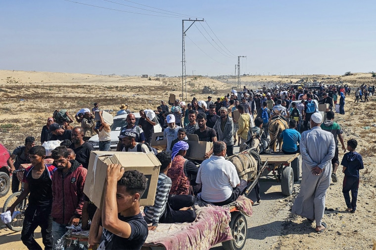 Los palestinos desplazados caminan por un camino.
