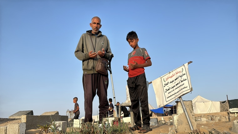 Ahmed Darwish, left, prays at a cemetery in Khan Younis on Friday.