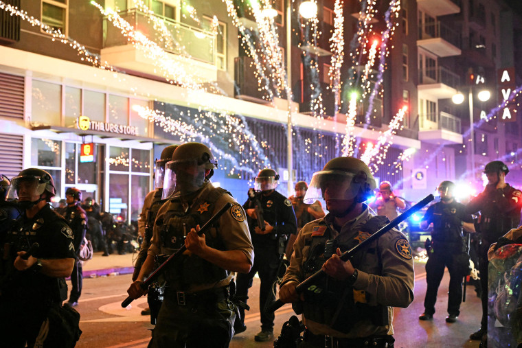 Fireworks explode behind Ventura County Sheriff's department deputies in riot gear 