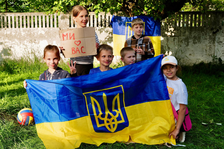 A radical of young children holding signs and a Ukraine flag