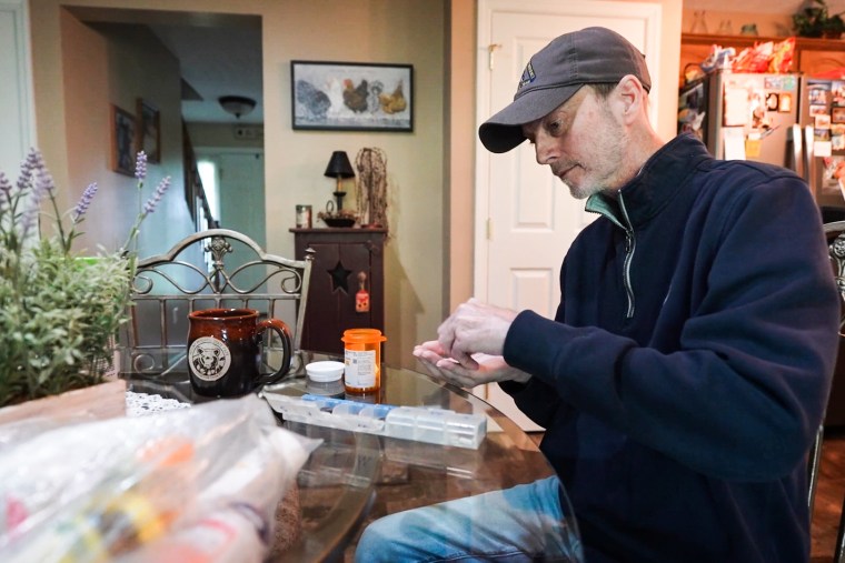 Eric Tennant prepares to take his pills at his kitchen table