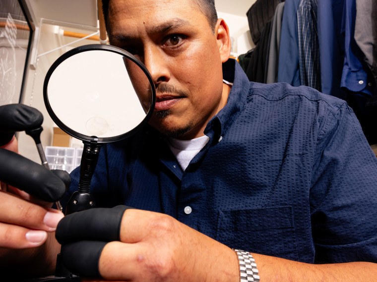 Mendoza looks through a magnifying glass in his closet workshop.