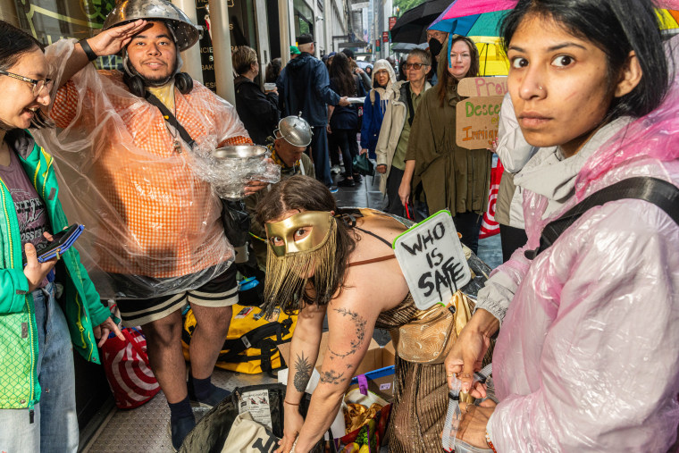 Image: Protestors in costume and holding signs.