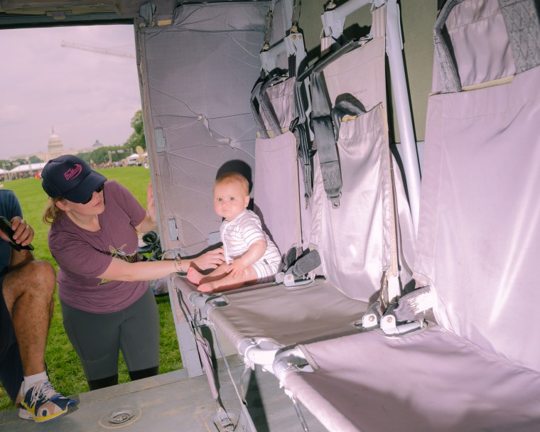 A baby sits inside a military helicopter