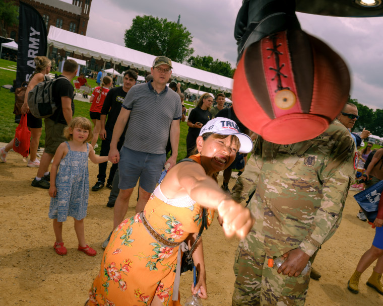 A woman wearing a Trump hat hits a punching bag while a young girl looks on.
