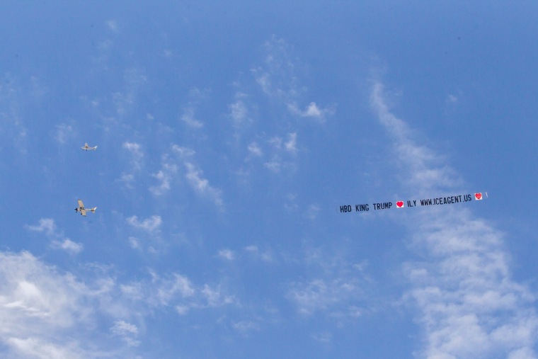 Image: An airplane in a blue sky with a large banner.