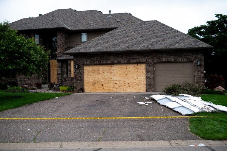 Boards cover the doors and windows outside of a home