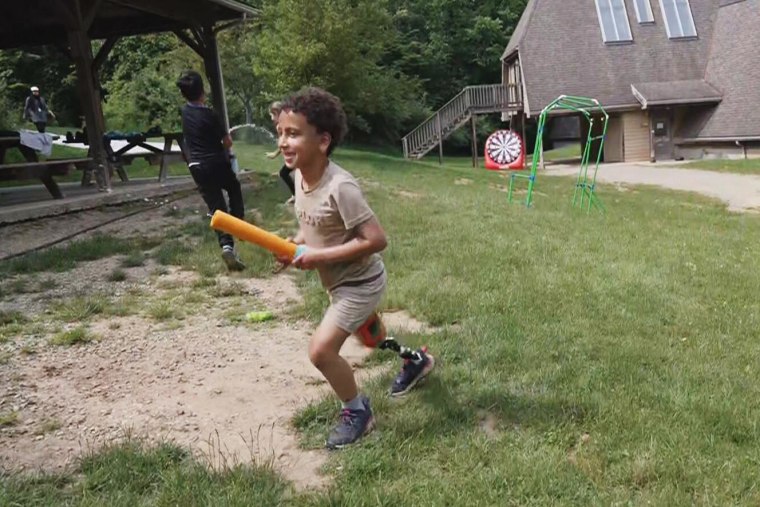 A lad with a prosthetic limb engages successful a h2o combat with different campers.