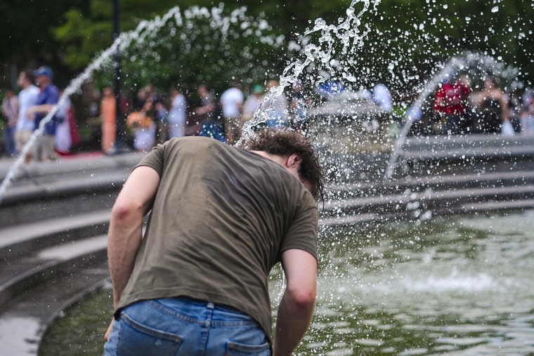 A person places their head under water streams at a fountain