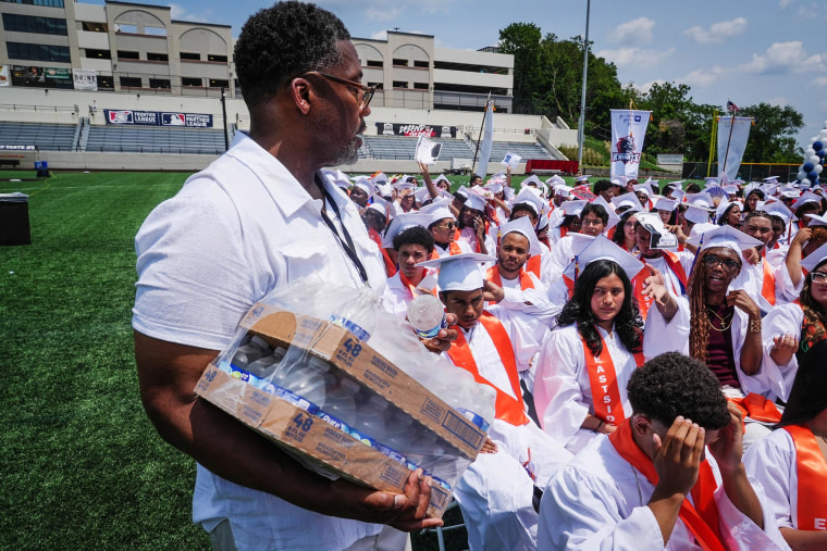 An administrator hands out water bottles to graduates during the Paterson Public Schools graduation at Hinchliffe Stadium, on Jun 23, 2025, in Paterson, N.J.