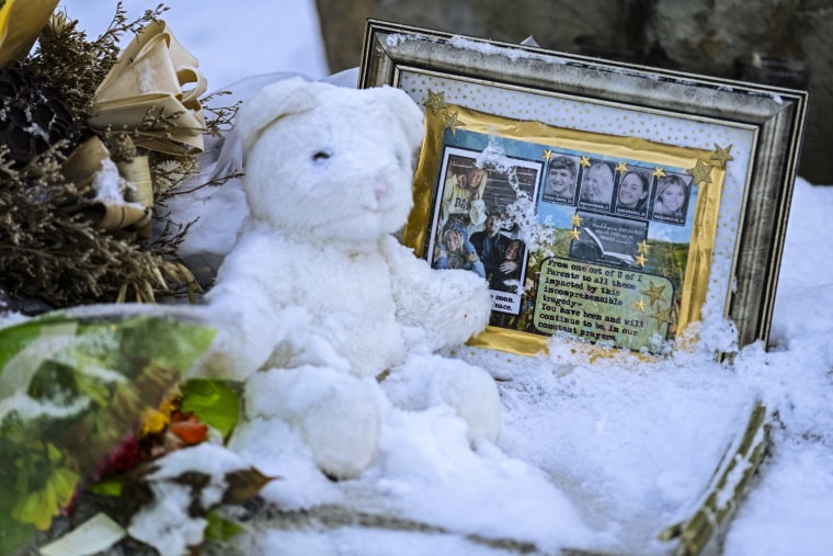 Flowers, a stuffed animal, and a framed image featuring the photos of the four people found dead at a house in Moscow, Idaho, rest in the snow in front of the house on Nov. 29, 2022. 