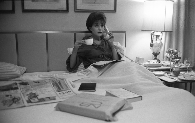 American broadcast journalist Barbara Walters talks on the telephone as she holds a cup of coffee in bed, New York, 1966.