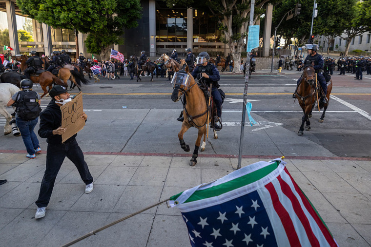 Agentes de la policía montada cargan con sus caballos contra una multitud para despejar un área cerca del Ayuntamiento mientras continúan las protestas en un área de una milla cuadrada del centro de Los Ángeles en respuesta a redadas de inmigración, 11 de junio de 2025, Los Ángeles, California.