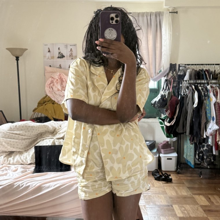 Photo of woman taking a mirror selfie in yellow, floral print pajamas.