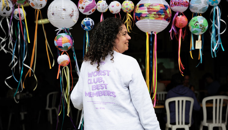 Randi Treilman, 46, poses for a portrait while wearing a sweatshirt that says "Worst Club, Best Members" on the back at Camp Breastie.