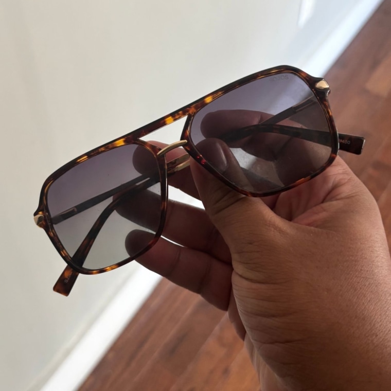 Person holding the Sojos Sunglasses with right hand.