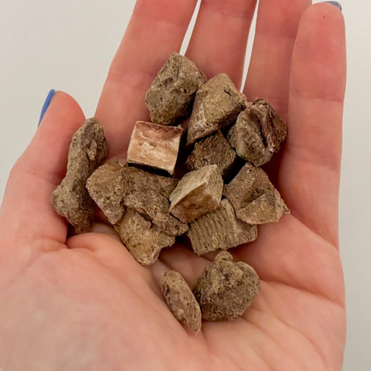 A few pieces of Vital Essentials’ Beef Liver Dog Treats in the palm of someone’s hand.