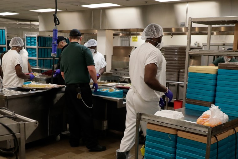 Workers, including some detainees, prepare trays containing meals