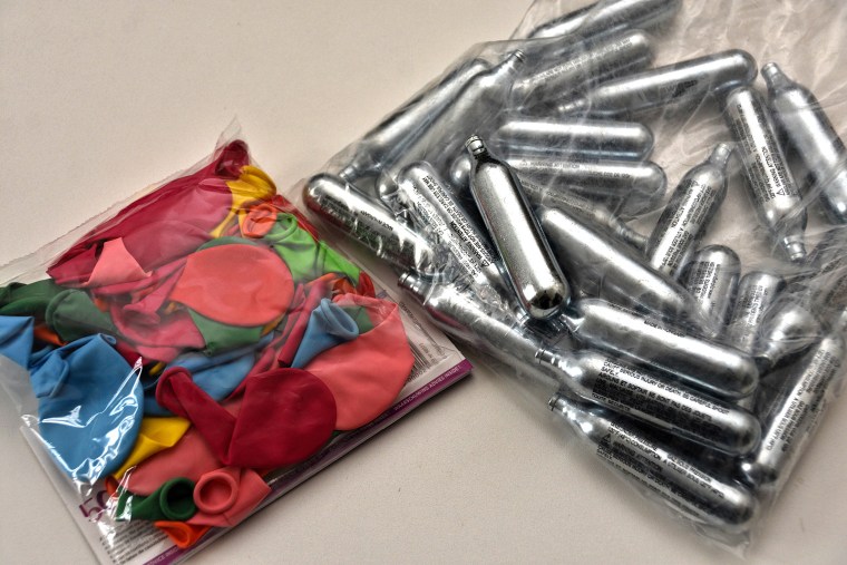 Balloons and nitrous oxide bottles are seen displayed on a table.