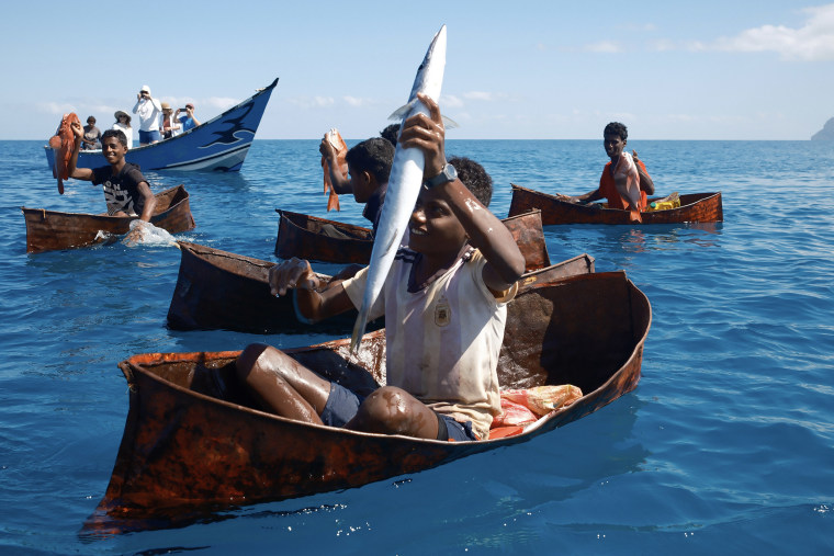Children catch fish using only a hook and line in boats made from welded oil drums.